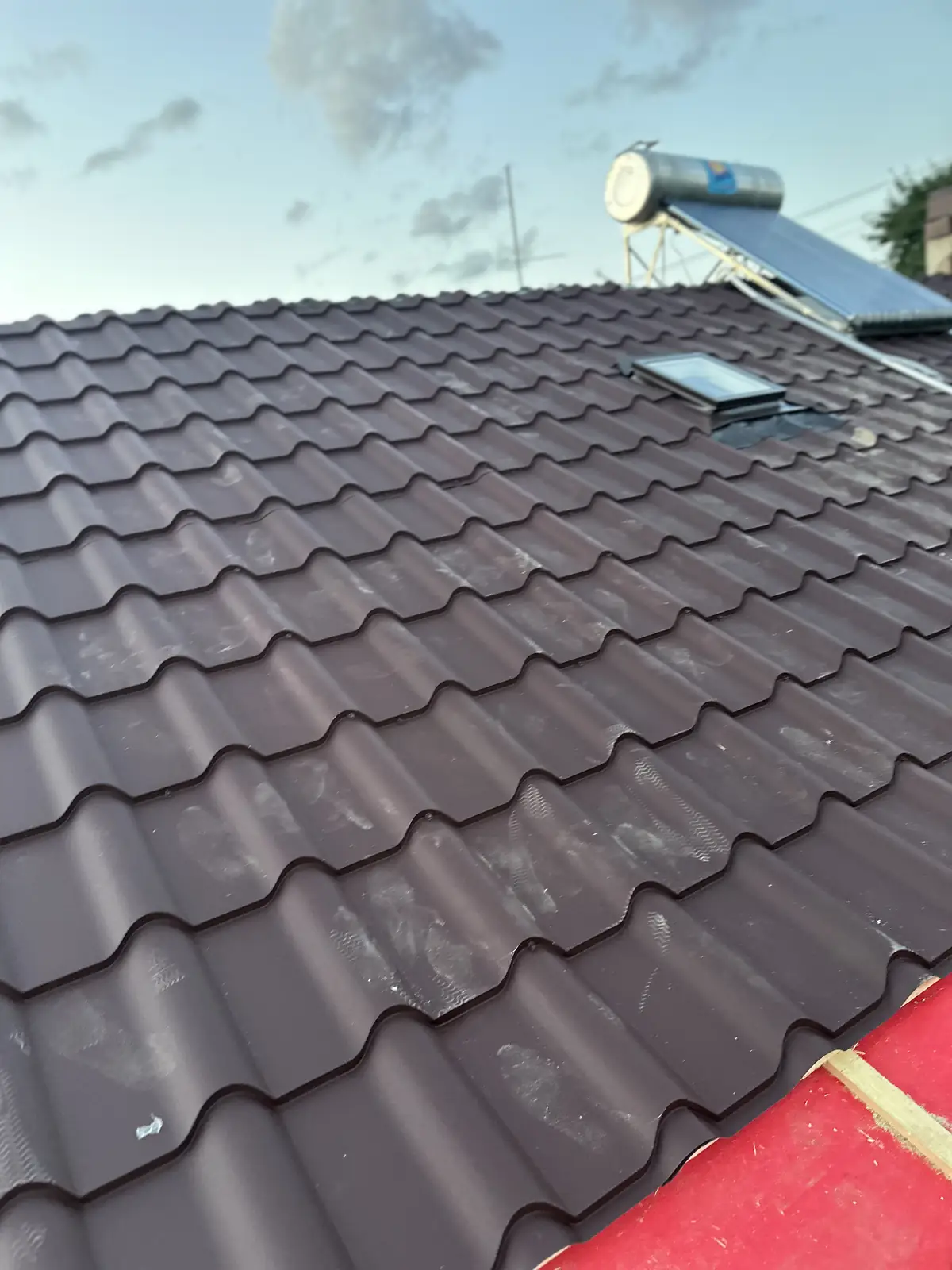 Versant cu țiglă metalică maro, fereastră de acoperiș și panou solar