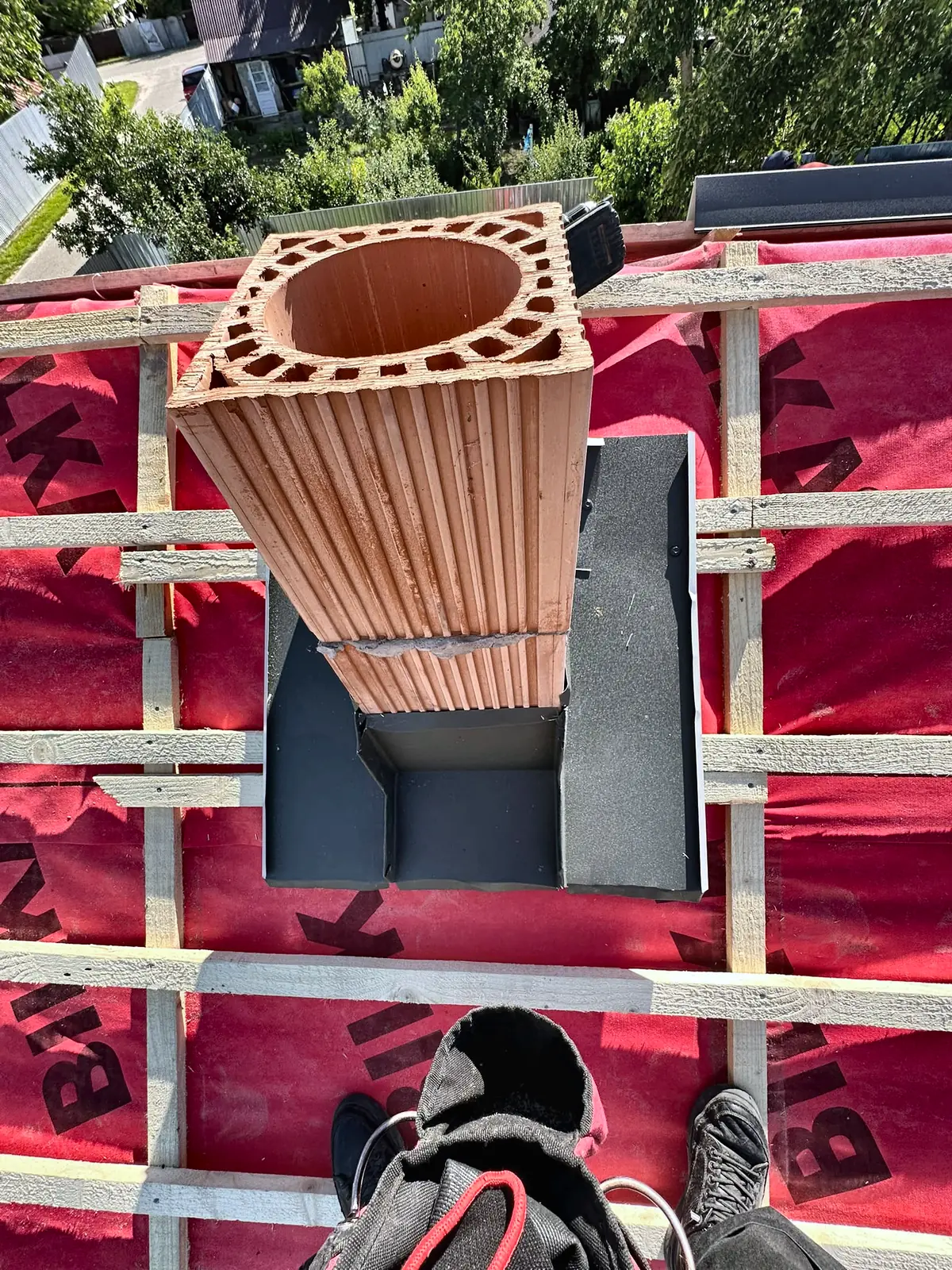 Coș de fum de ceramică ieșind prin folia anticondens, cu șorțul de racord montat la bază.