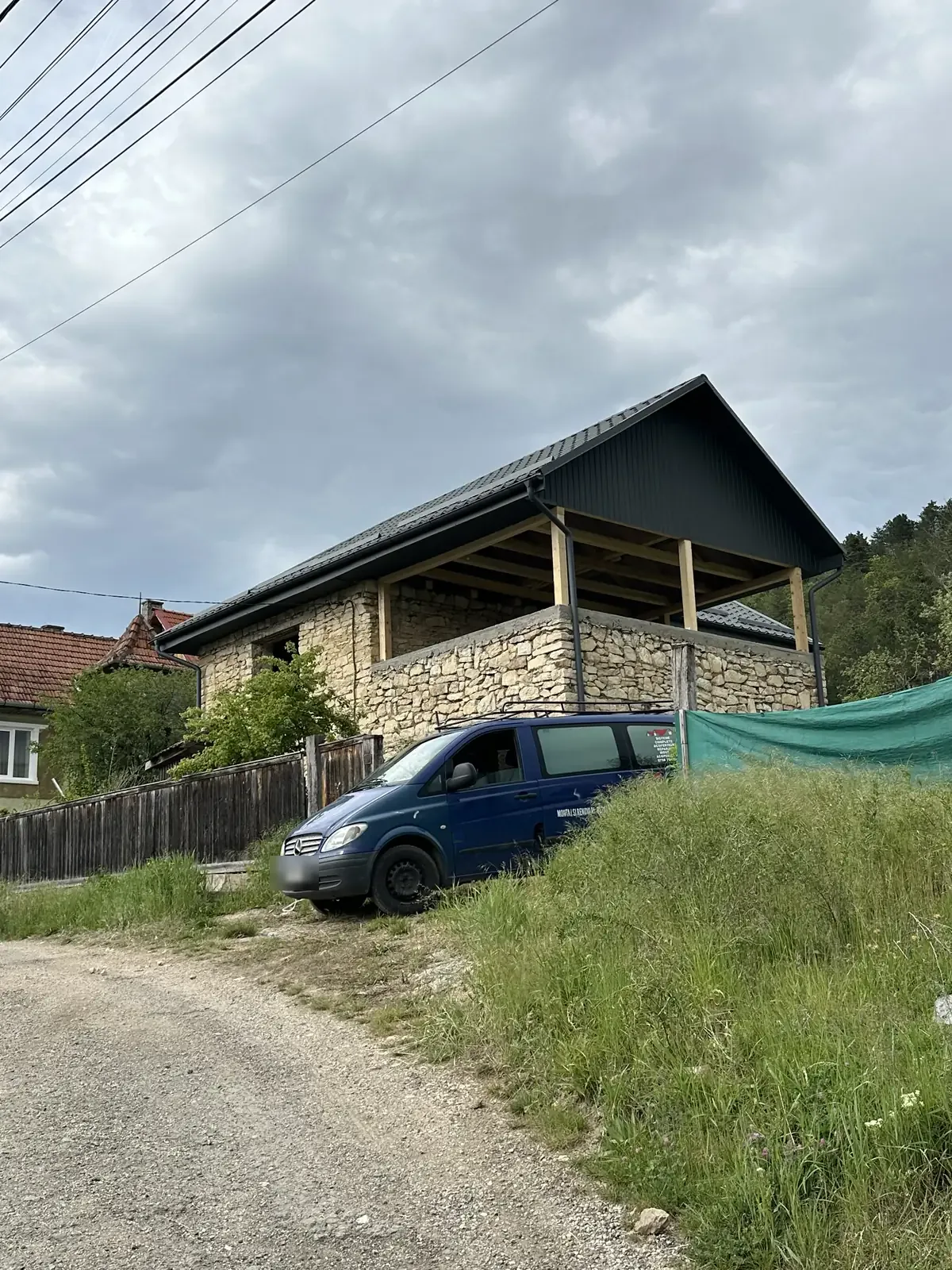 Casă cu acoperiș nou din tablă antracit, văzută dinspre drum, la finalul lucrării.