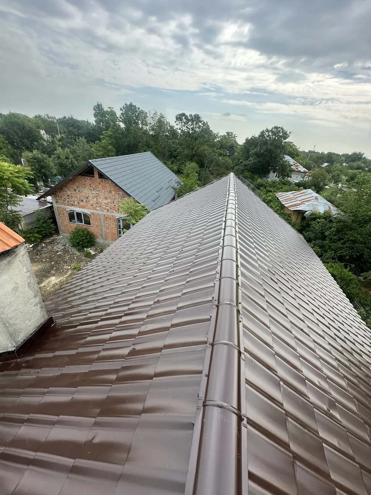Acoperiș terminat cu țiglă metalică maro și coame rotunde pe linia coamei