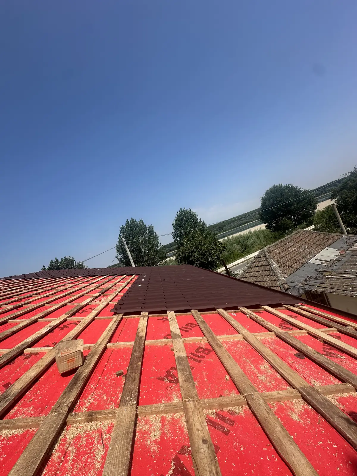 Folia anticondens și șipca montate pe versant, lângă un acoperiș deja finalizat